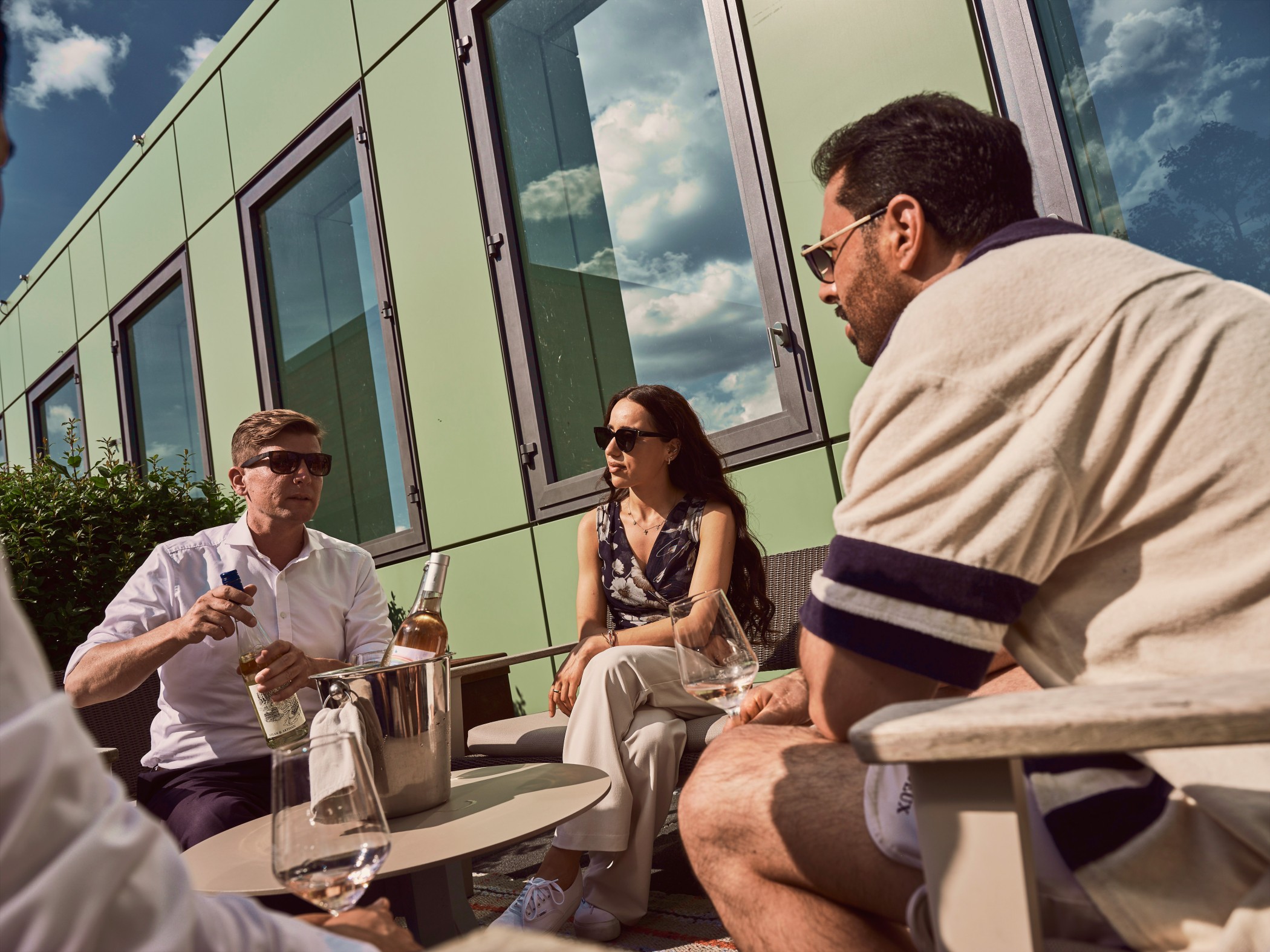 Gruppe von Freunden genießt Wein und Gespräche auf der Dachterrasse des WIN WIN im Düsseldorfer Medienhafen.