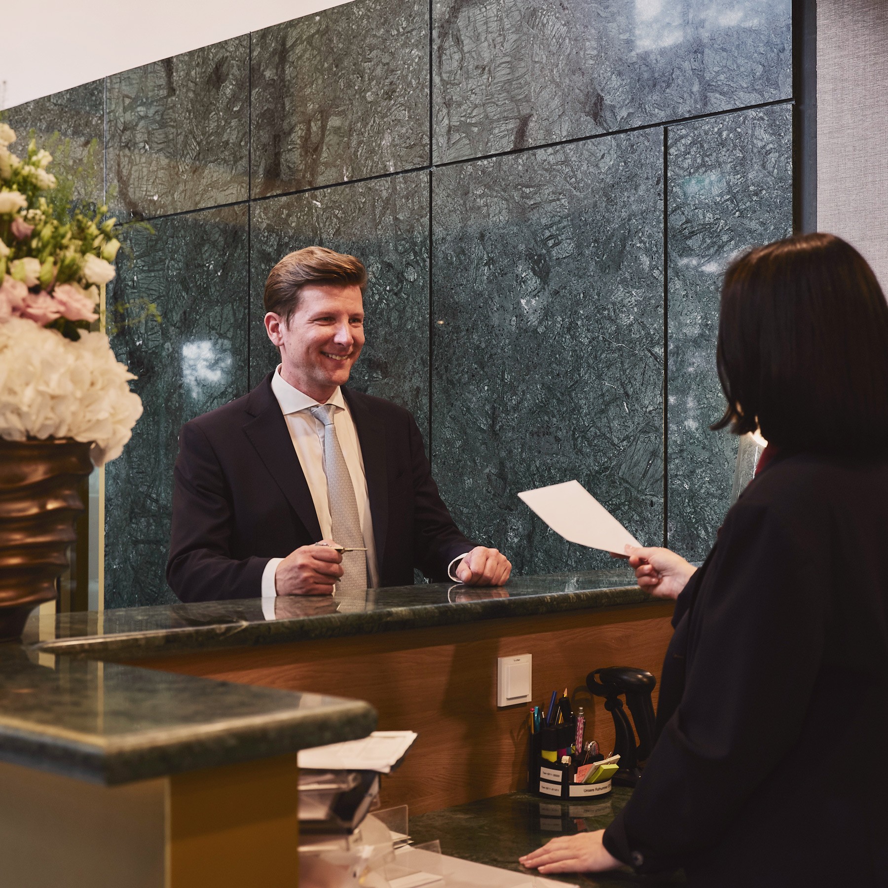 Concierge-Service hilft einem Bewohner in der Lobby des WIN WIN im Medienhafen Düsseldorf