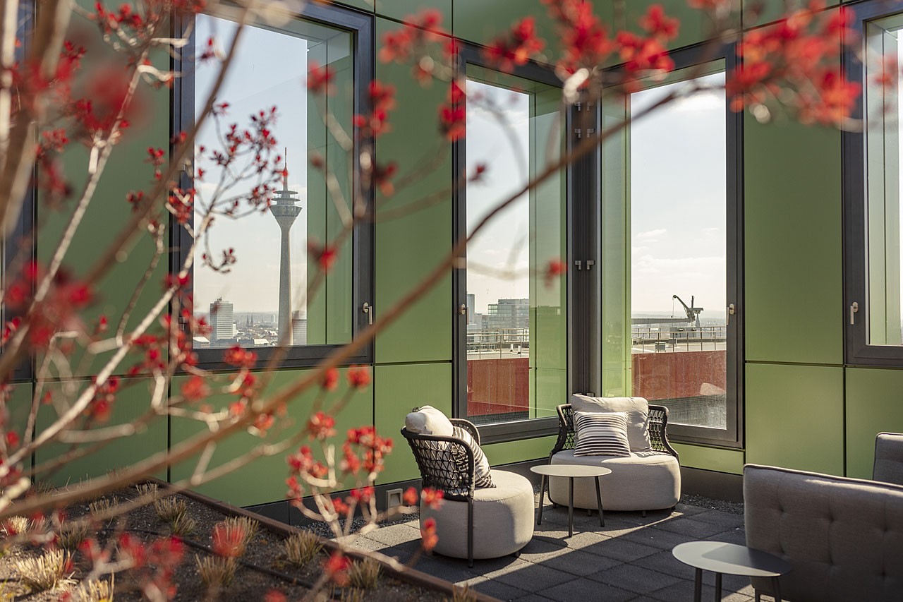 Dachterrasse der WIN WIN Türme mit Lounge-Möbeln und Blick auf den Rheinturm im Medienhafen Düsseldorf
