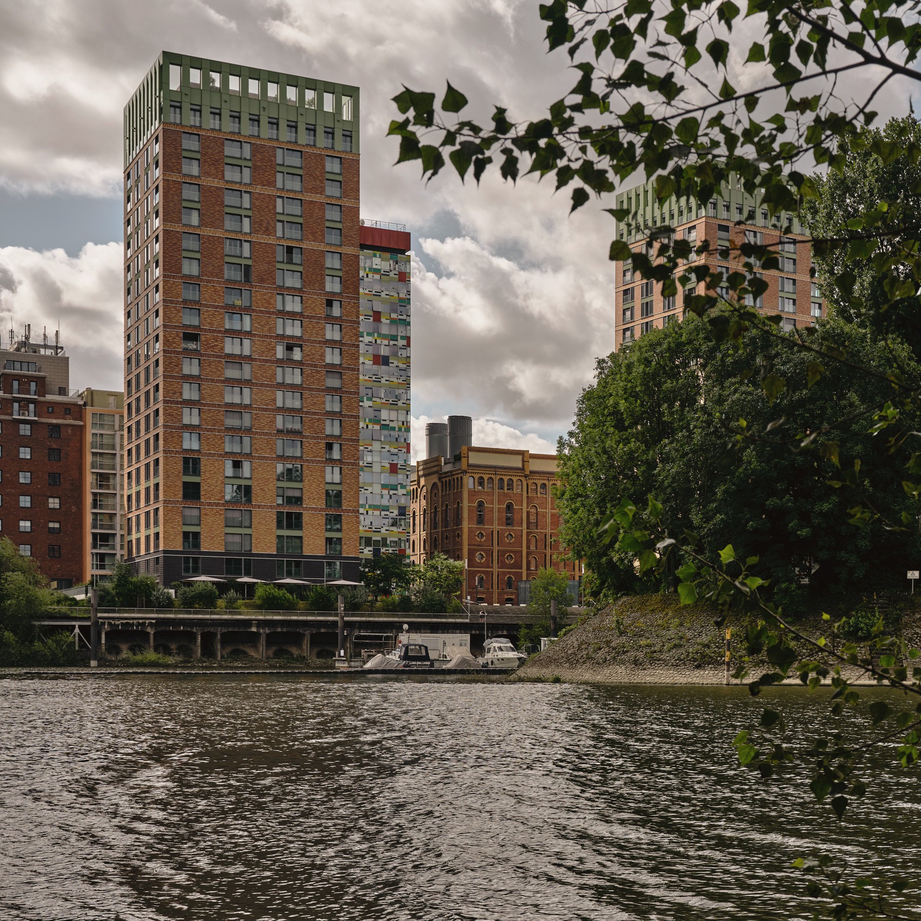 Blick auf die WIN WIN Türme im Medienhafen Düsseldorf, gesehen vom Hafenbecken und eingerahmt von Bäum