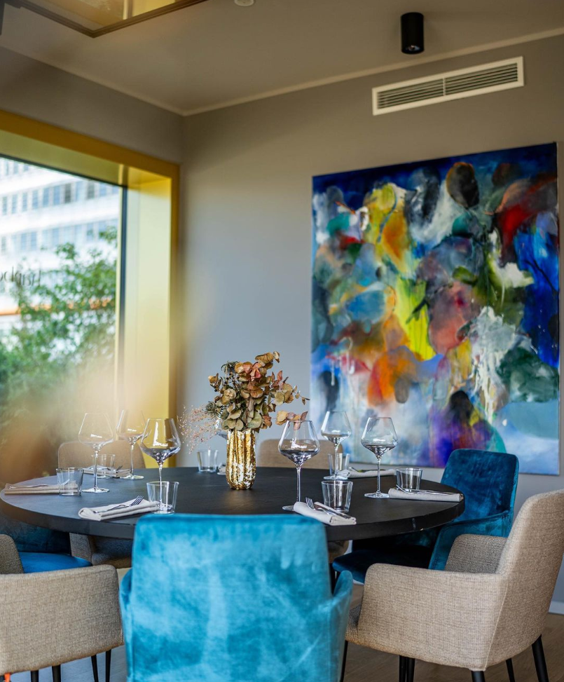 Modern gedeckter Esstisch mit farbenfroher Kunst und türkis-beigen Stühlen im WIN WIN Medienhafen Düsseldorf