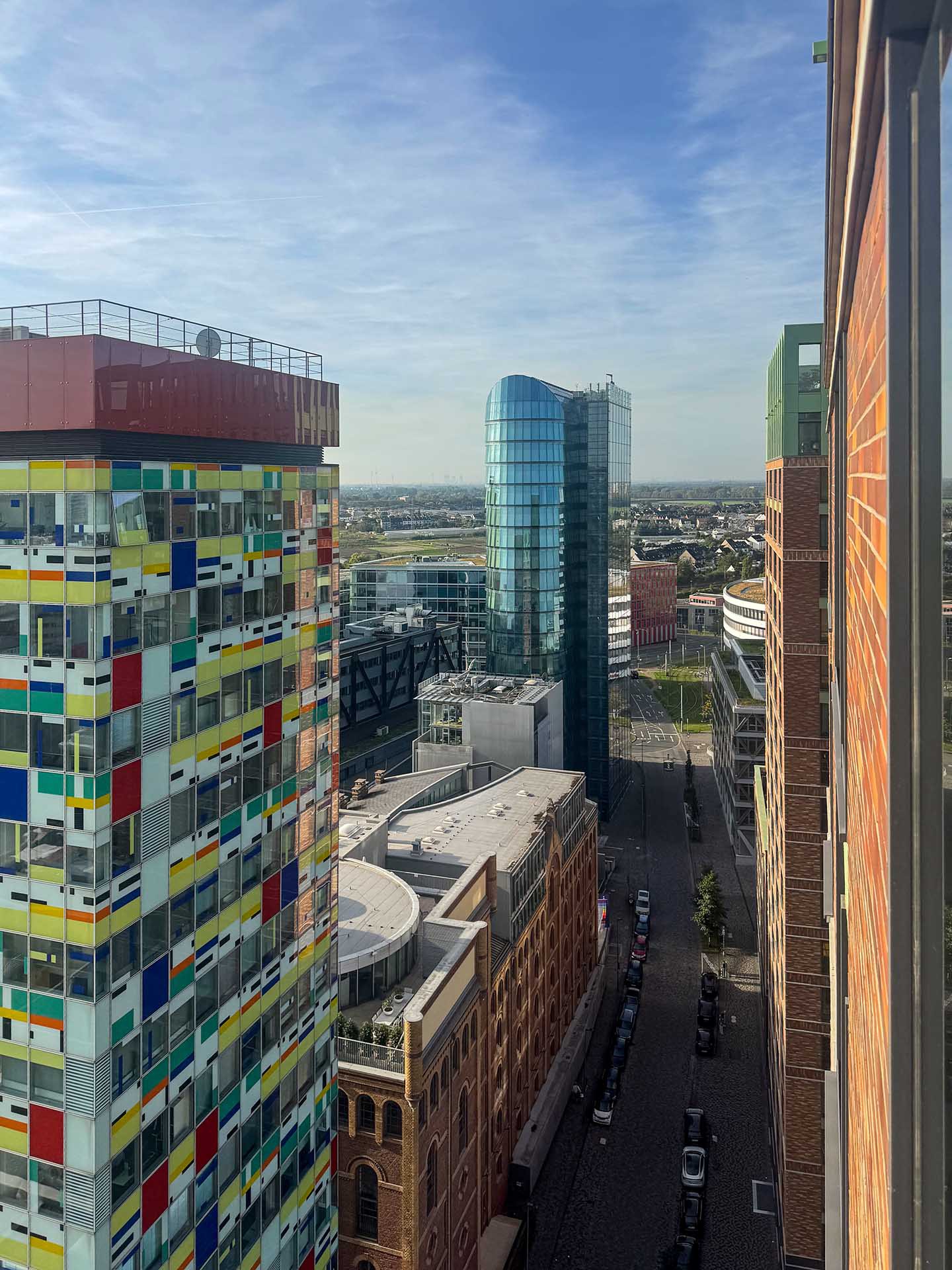Blick aus der High Five N° One in die Straße zwischen dem bunten Colorium und einer Backsteinfassade, hinten ein Glasturm