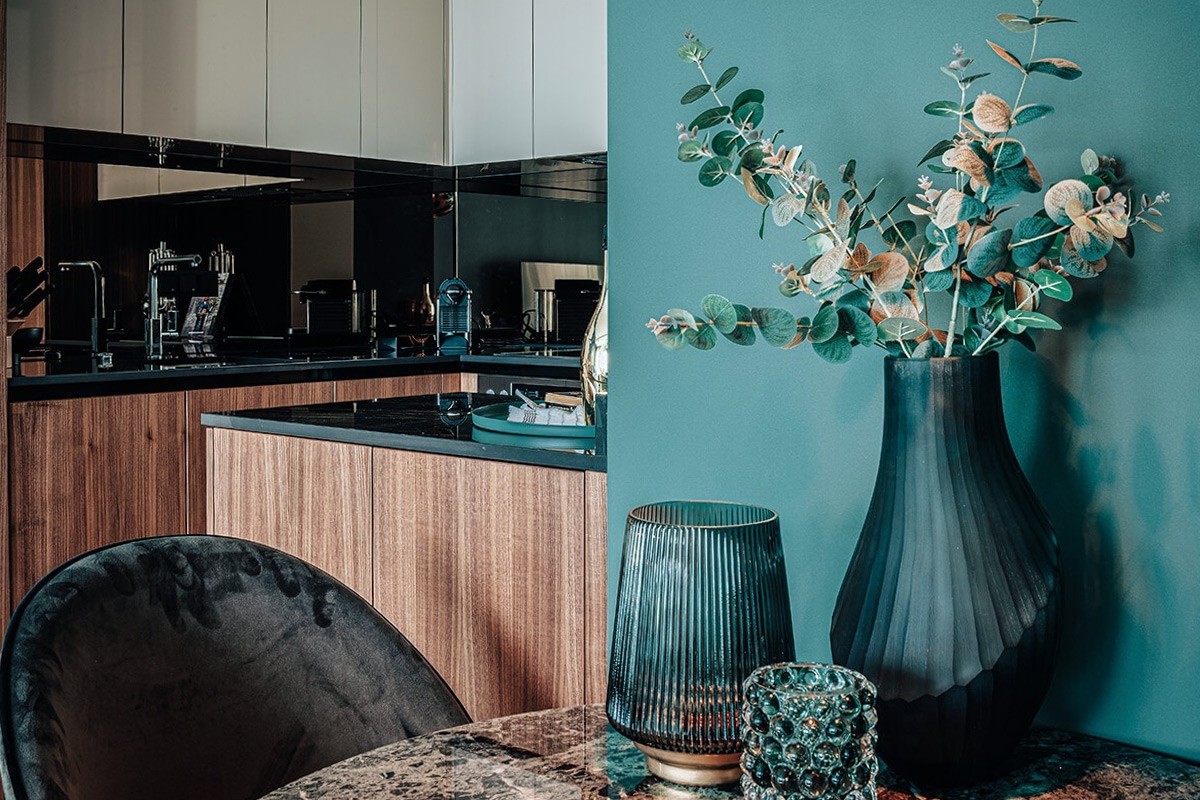 Detailaufnahme eines stilvoll dekorierten Esstisches mit Vase und Blick in die moderne Küche der WIN WIN Luxuswohnung im Düsseldorfer Medienhafen