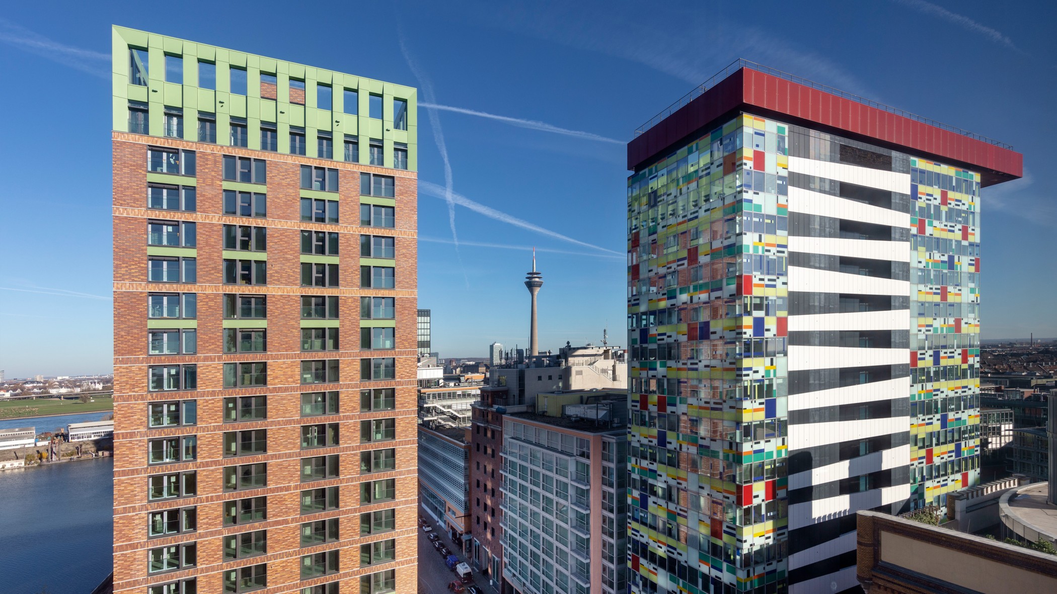 Blick auf einen WIN WIN Turm im Medienhafen Düsseldorf mit Sicht auf den farbigen Colorium-Turm und den Rheinturm im Hintergrund.