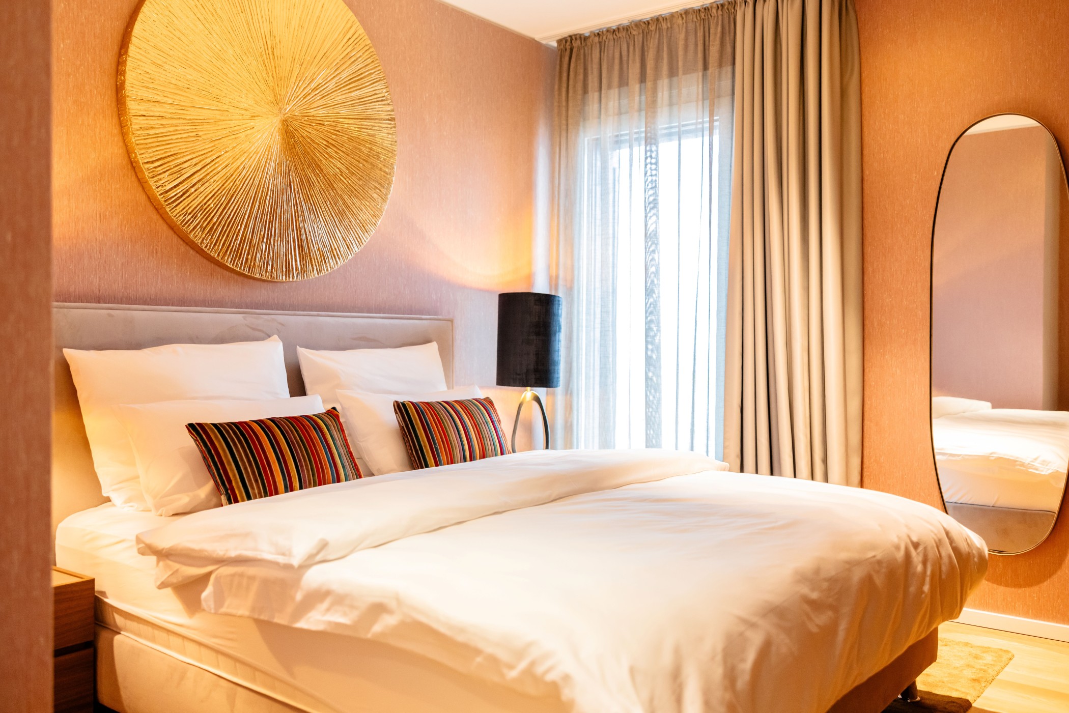 Luxuriöses Schlafzimmer im WIN WIN Medienhafen Düsseldorf mit großem Bett, goldenem Wanddekor und bodentiefen Vorhängen