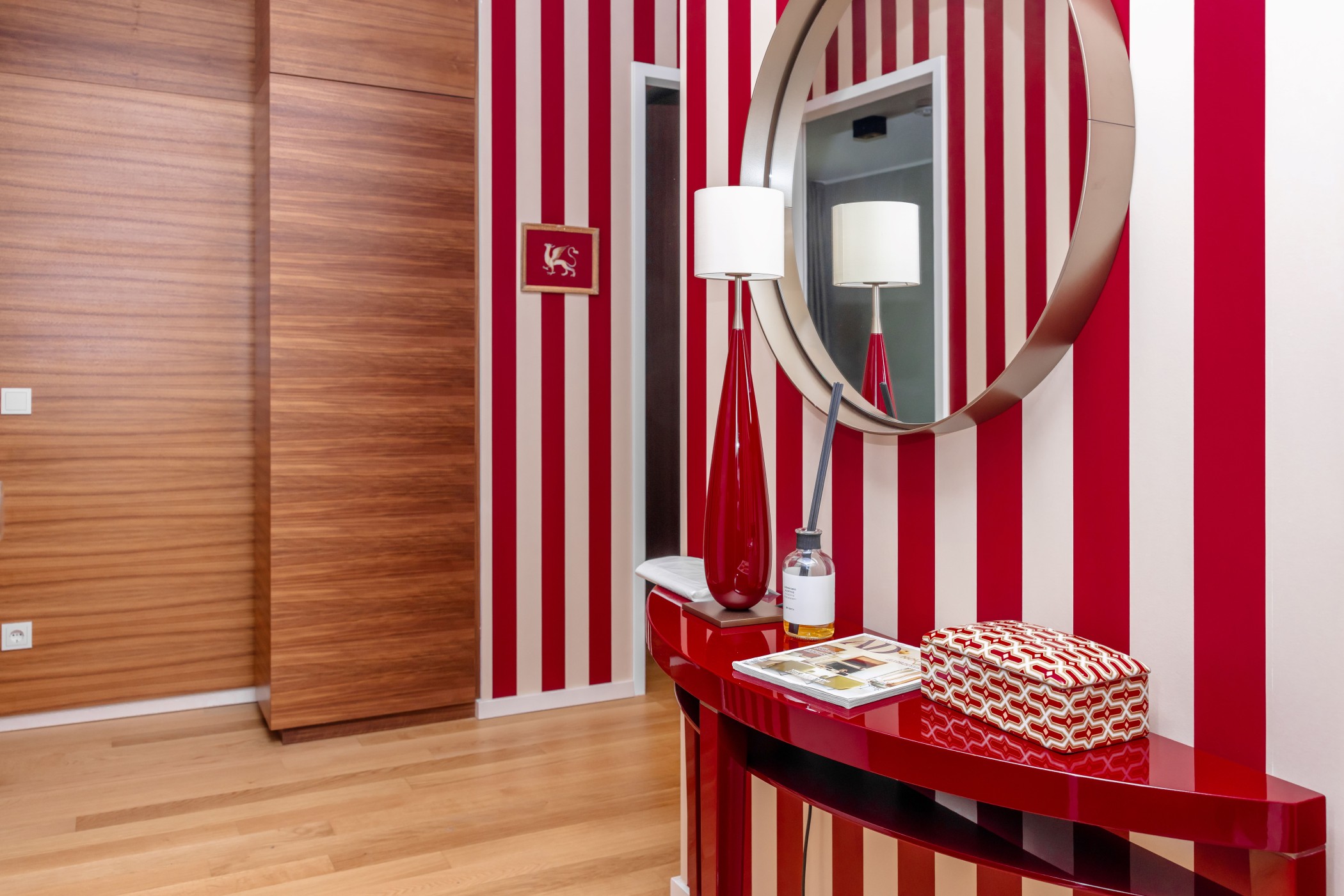 Eingangsbereich mit rot-weiß gestreifter Designer-Tapete, rundem Spiegel und rotem Konsolentisch im WIN WIN Medienhafen Düsseldorf