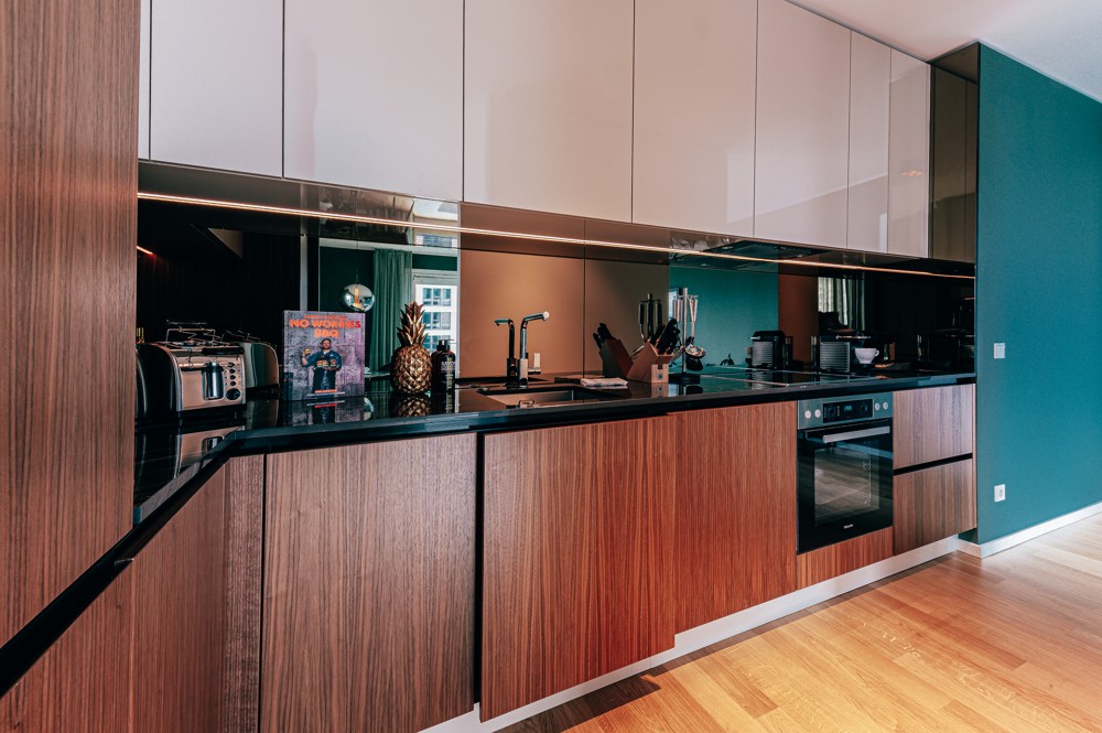 Moderne Einbauküche mit Holzfronten, hochglänzenden Oberschränken und durchgehendem Spiegelrückwandpanel im WIN WIN, Medienhafen Düsseldorf