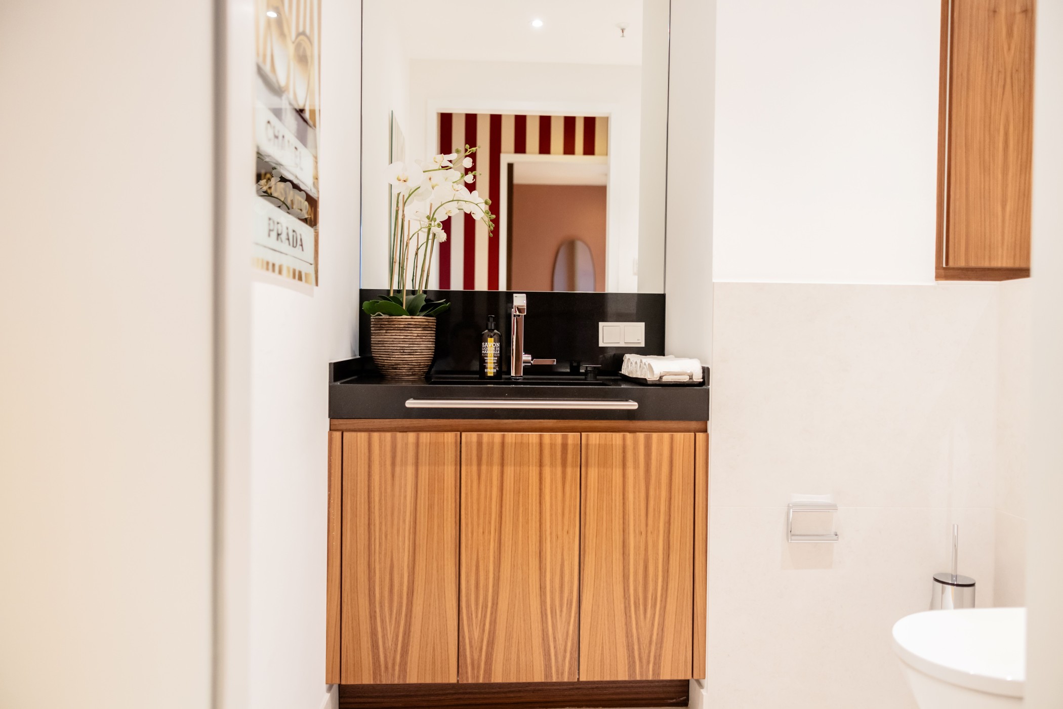 Modernes Gäste-WC mit dunkler Stein-Waschtischplatte, hochwertigen Holzfronten und großem Spiegel in einer Luxuswohnung im Düsseldorfer Medienhafen