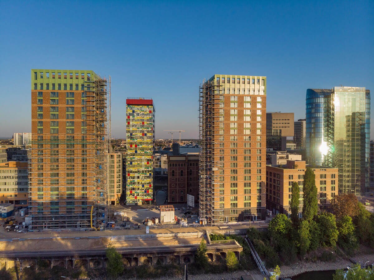 Luftaufnahme der WIN-WIN-Türme im Düsseldorfer Medienhafen während der Bauphase bei Sonnenuntergang, mit eingerüsteten Fassaden, Wasserlage und benachbarten Hochhäusern