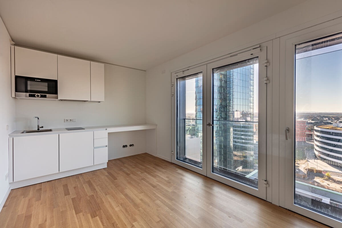 Moderne weiße Einbauküche mit bodentiefen Fenstern und Blick auf die Architektur im WIN WIN Medienhafen Düsseldorf