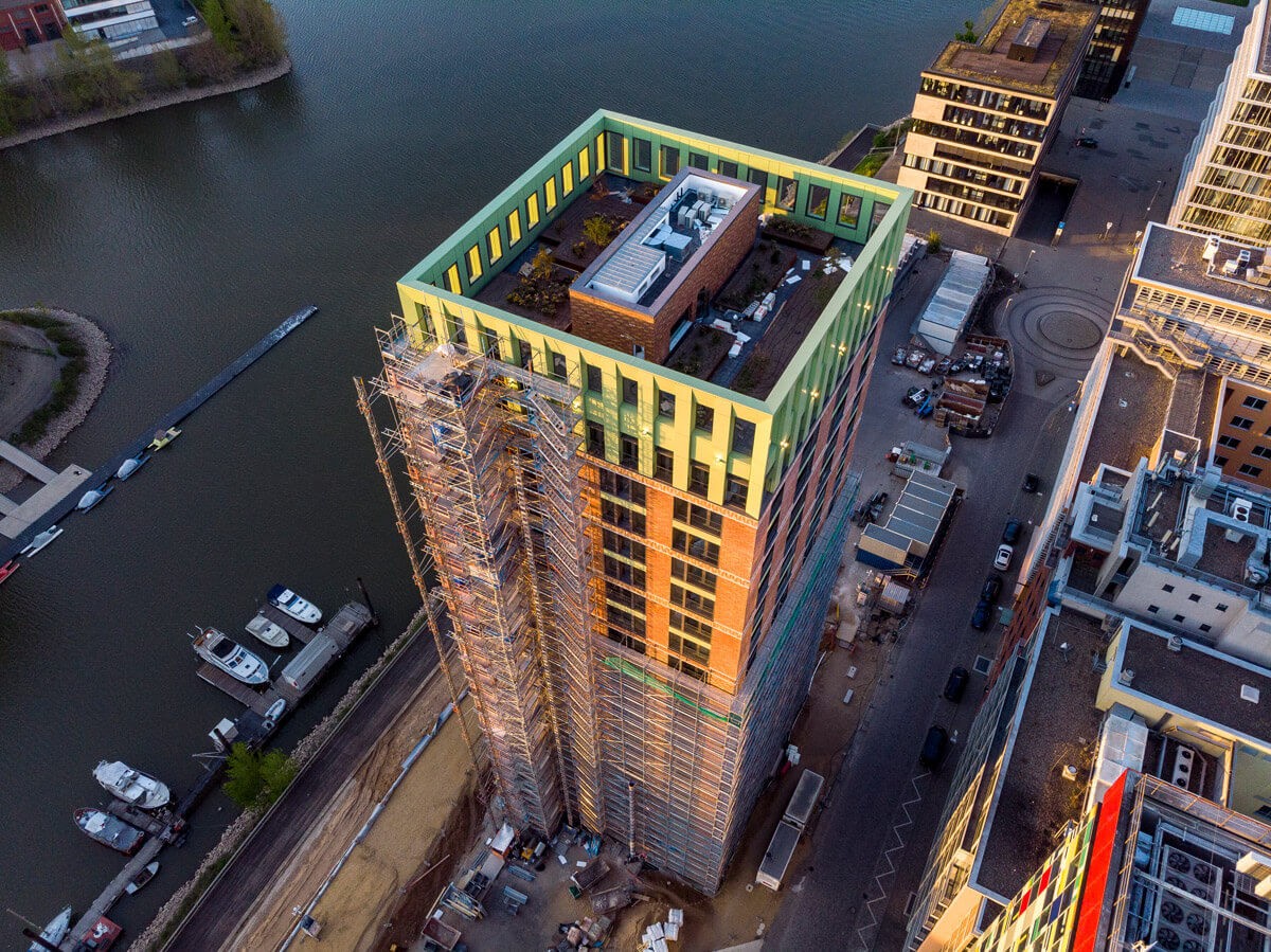 Baustellenaufnahme des WIN WIN Wohnturms im Düsseldorfer Medienhafen aus der Vogelperspektive mit Gerüst, Hafenbecken und umliegender moderner Architektur