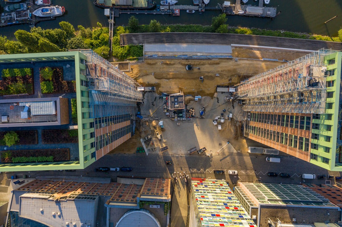 Drohnenaufnahme der WIN WIN Tower-Baustelle im Düsseldorfer Medienhafen mit Blick zwischen den beiden Gebäuden auf das Baufeld und die umliegenden Hafenanlagen