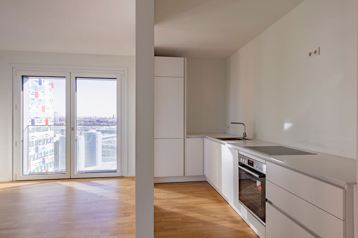 Minimalistische weiße Einbauküche mit bodentiefen Fenstern und Weitblick über den Medienhafen Düsseldorf im WIN WIN Gebäude