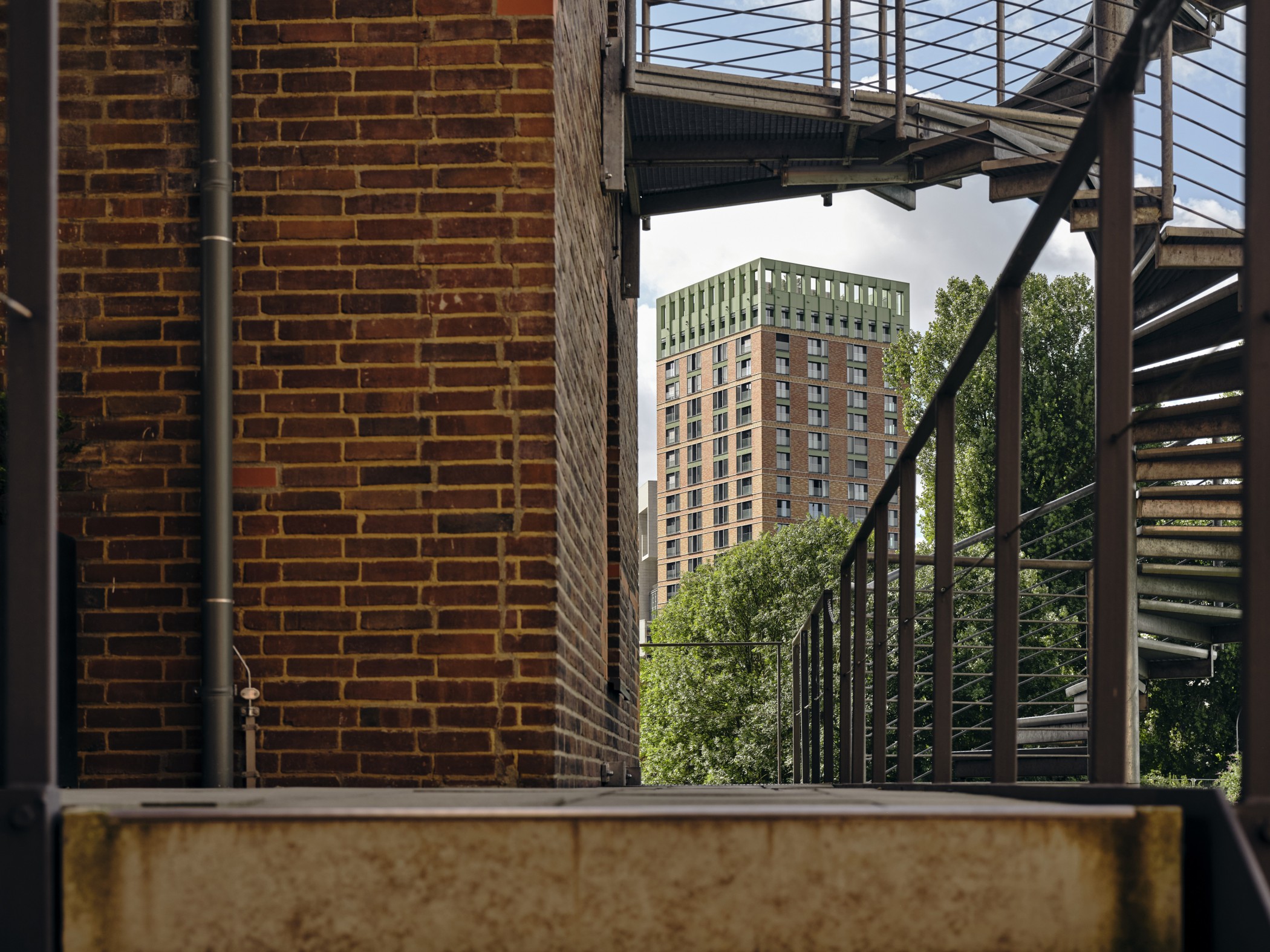 Blick auf einen WIN WIN Turm im Medienhafen Düsseldorf, eingerahmt von industriellen Stahlstrukturen und Backsteinarchitektur im Vordergrund.