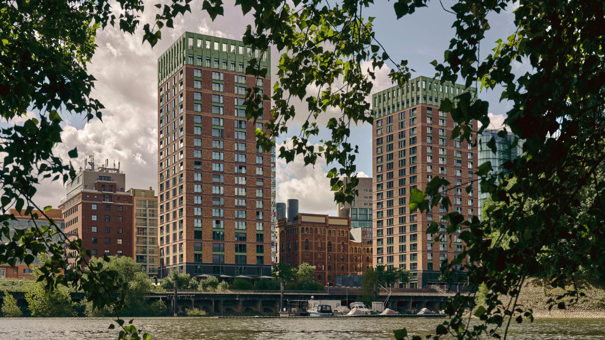 WIN WIN Türme im Medienhafen Düsseldorf, gesehen durch einen natürlichen Rahmen aus belaubten Ästen.